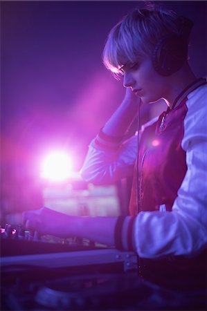 Female dj listening to headphones while playing music in bar Photographie de stock - Premium Libres de Droits, Code: 6109-08944496