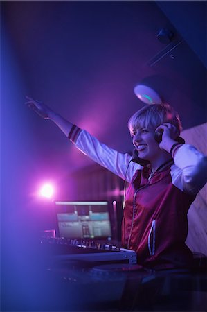 deejay (female) - Pretty female dj waving her hand while playing music in bar Foto de stock - Sin royalties Premium, Código: 6109-08944499