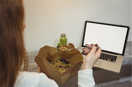simsearch:649-06352854,k - Rear view of woman eating salad while looking at laptop Stock Photo - Premium Royalty-Free, Code: 6109-08944410