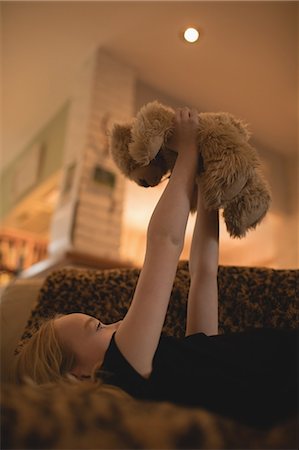 simsearch:6109-06194711,k - Girl lying on sofa and playing with teddy bear in living room at home Foto de stock - Royalty Free Premium, Número: 6109-08944544