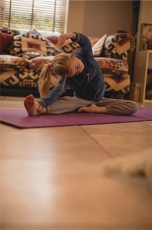 pilates mat - Girl performing yoga in living room at home Photographie de stock - Premium Libres de Droits, Code: 6109-08944549