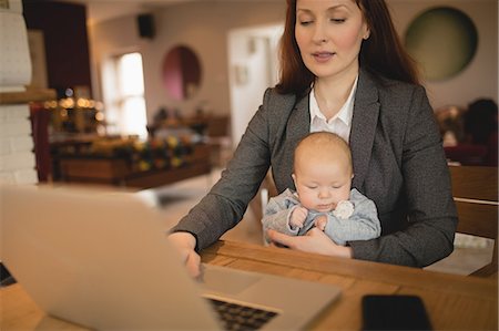 simsearch:6109-08944518,k - Mother using laptop while holding her baby at  home Fotografie stock - Premium Royalty-Free, Codice: 6109-08944576