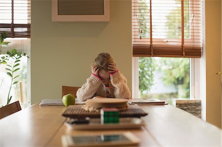 sleepy girl is sad - Frustrated girl sitting at table and studying in living room at home Stock Photo - Premium Royalty-Free, Code: 6109-08944582