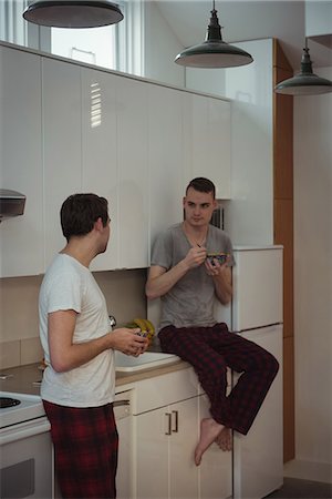 simsearch:6109-08944593,k - Gay couple having breakfast in kitchen at home Stock Photo - Premium Royalty-Free, Code: 6109-08944588