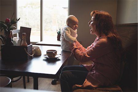 simsearch:6109-08944514,k - Happy mother playing with her baby in café Foto de stock - Sin royalties Premium, Código: 6109-08944508