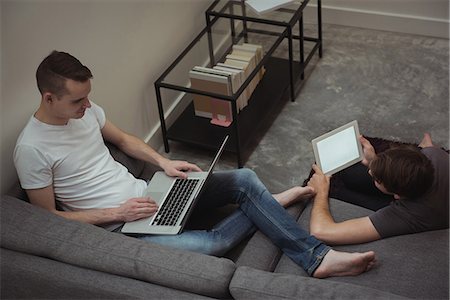 simsearch:6109-08804829,k - Gay couple using digital tablet and laptop in living room at home Stock Photo - Premium Royalty-Free, Code: 6109-08944643
