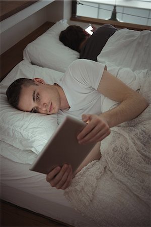simsearch:6102-08184099,k - Man using digital tablet while lying on the bed with his gay partner in bedroom Foto de stock - Royalty Free Premium, Número: 6109-08944649