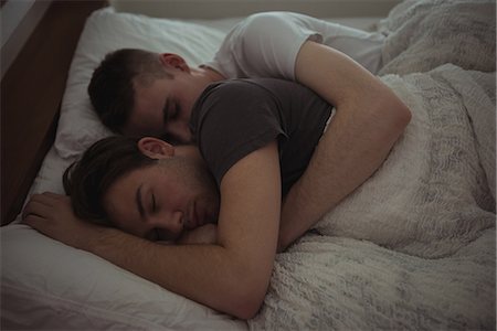 Gay couple embracing while sleeping on bed in bedroom Foto de stock - Sin royalties Premium, Código: 6109-08944651