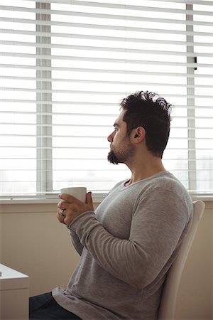 simsearch:6115-08416168,k - Thoughtful man holding a coffee cup at home Stock Photo - Premium Royalty-Free, Code: 6109-08944685