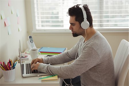 simsearch:6109-08945013,k - Side view of man using laptop while sitting at desk Stock Photo - Premium Royalty-Free, Code: 6109-08944691