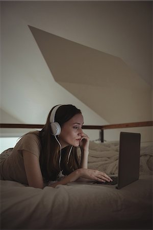 simsearch:6109-06194493,k - Woman with headphones using laptop on bed at home Stockbilder - Premium RF Lizenzfrei, Bildnummer: 6109-08944602