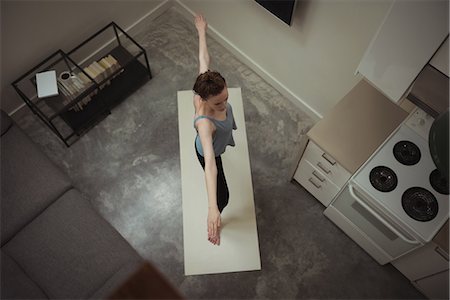 simsearch:6109-08435544,k - Woman performing stretching exercise in kitchen at home Photographie de stock - Premium Libres de Droits, Code: 6109-08944613