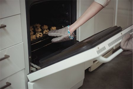 Mid section of woman baking cookies in the oven Stock Photo - Premium Royalty-Free, Code: 6109-08944624