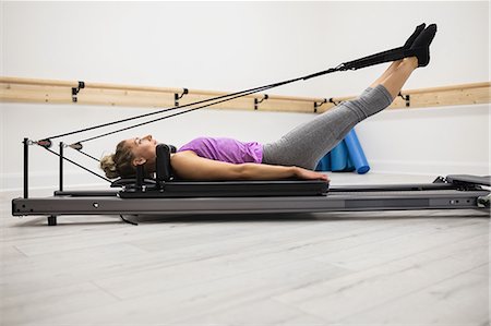 simsearch:6109-08944773,k - Woman exercising on reformer in gym Photographie de stock - Premium Libres de Droits, Code: 6109-08944773