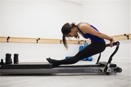 simsearch:6108-06906978,k - Woman exercising on reformer in gym Photographie de stock - Premium Libres de Droits, Code: 6109-08944778