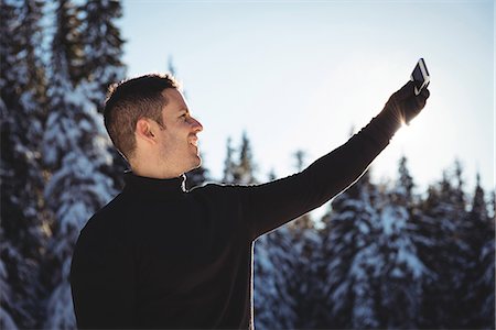 simsearch:6126-09103925,k - Smiling man taking selfie on mobile phone during winter Stock Photo - Premium Royalty-Free, Code: 6109-08944864