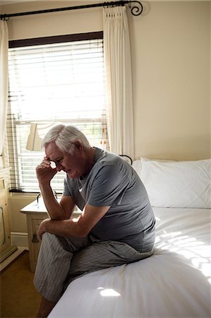 sadness - Worried senior man sitting on bed in the bedroom at home Stock Photo - Premium Royalty-Free, Code: 6109-08944893