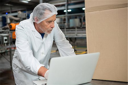 Serious male worker using laptop in cold drink factory Stock Photo - Premium Royalty-Free, Code: 6109-08945050