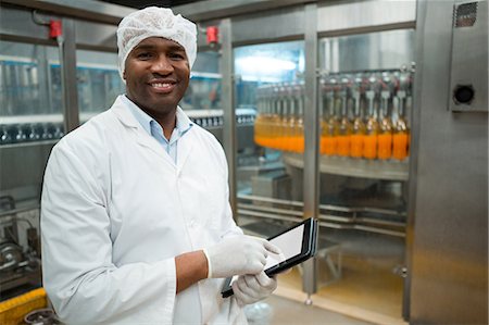 Portrait of male worker holding digital tablet while inspecting juice bottles in factory Stock Photo - Premium Royalty-Free, Code: 6109-08945062