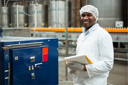 Smiling male worker with clipboard standing by machine in juice factory Stock Photo - Premium Royalty-Free, Code: 6109-08945068
