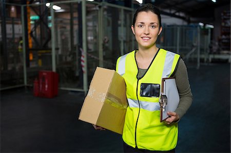engineers and factory workers - Portrait of young female worker carrying box and clipboard in warehouse Stock Photo - Premium Royalty-Free, Code: 6109-08945086