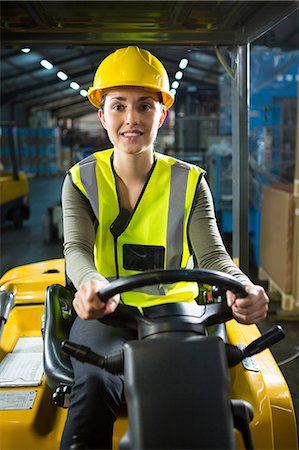 Portrait of beautiful female worker driving forklift in warehouse Stock Photo - Premium Royalty-Free, Code: 6109-08945092