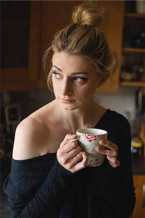 simsearch:6109-08802258,k - Thoughtful woman holding a coffee cup in kitchen at home Photographie de stock - Premium Libres de Droits, Code: 6109-08945013