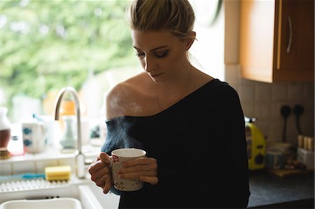 simsearch:6109-08944356,k - Thoughtful woman holding a coffee cup in kitchen at home Stock Photo - Premium Royalty-Free, Code: 6109-08945012