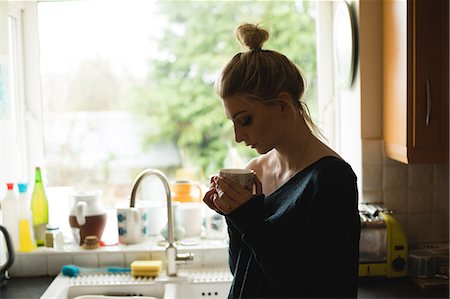 simsearch:6109-08944685,k - Thoughtful woman holding a coffee cup in kitchen at home Stock Photo - Premium Royalty-Free, Code: 6109-08945015