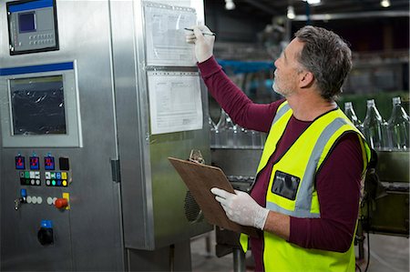 Senior manual worker analyzing machinery in factory Stock Photo - Premium Royalty-Free, Code: 6109-08945171