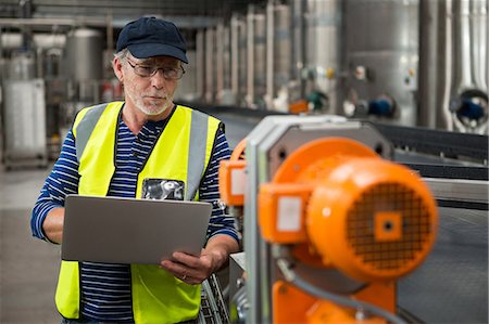 Manual worker analyzing machinery in factory Stock Photo - Premium Royalty-Free, Code: 6109-08945174