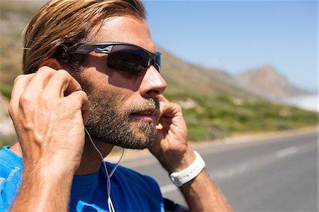 Close up of athlete listening music from headphones against sky Stock Photo - Premium Royalty-Free, Code: 6109-08945178