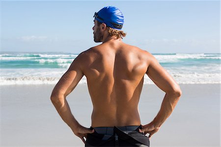 Rear view of shirtless athlete standing at beach against sky Stock Photo - Premium Royalty-Free, Code: 6109-08945190