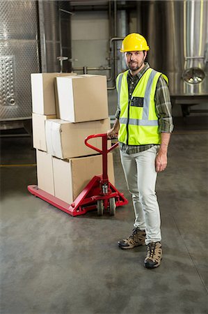 Full length portrait of male worker pulling trolley in warehouse Stock Photo - Premium Royalty-Free, Code: 6109-08945126