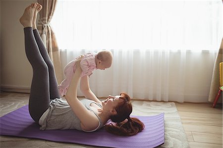 someone laying down with their feet up - Full length of mother carrying baby while lying on exercise mat at home Stock Photo - Premium Royalty-Free, Code: 6109-08945243