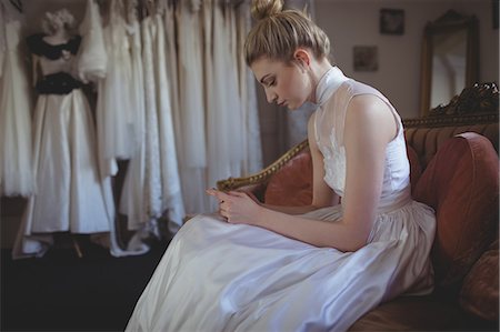 Young bride using mobile phone in a boutique Stock Photo - Premium Royalty-Free, Code: 6109-08945261