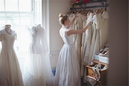 simsearch:670-06450369,k - Young bride selecting wedding dress from clothes hanger in a boutique Photographie de stock - Premium Libres de Droits, Code: 6109-08945280