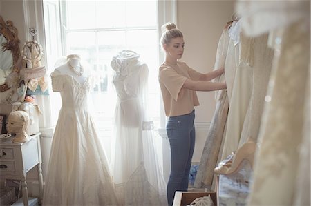 simsearch:670-06450341,k - Young woman selecting wedding dress from clothes hanger in a boutique Photographie de stock - Premium Libres de Droits, Code: 6109-08945291