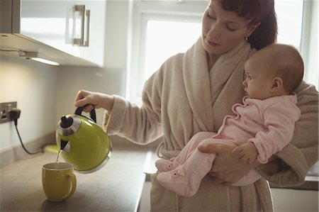 Loving mother carrying baby while making coffee in domestic kitchen Photographie de stock - Premium Libres de Droits, Code: 6109-08945232