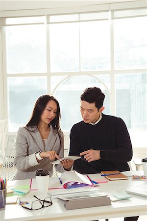 simsearch:6109-08945361,k - Male and Female executives discussing over digital tablet at desk in office Stock Photo - Premium Royalty-Free, Code: 6109-08945340