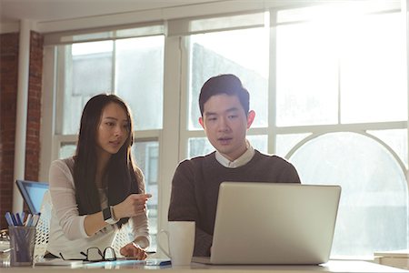 Male and female executives discussing over laptop at desk in office Photographie de stock - Premium Libres de Droits, Code: 6109-08945349