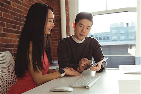 simsearch:6109-08945310,k - Male and Female executives discussing over digital tablet at desk in office Photographie de stock - Premium Libres de Droits, Code: 6109-08945351