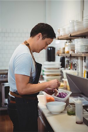 simsearch:6109-08489857,k - Side view of male chef adding chopped cabbage into bowl in commercial kitchen Stock Photo - Premium Royalty-Free, Code: 6109-08945386