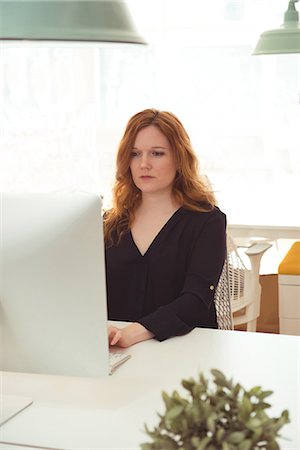 simsearch:6109-08945337,k - Female executive working on computer at desk in office Fotografie stock - Premium Royalty-Free, Codice: 6109-08945319
