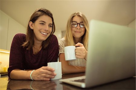 simsearch:6109-08763934,k - Happy friends using laptop while having coffee at home Stock Photo - Premium Royalty-Free, Code: 6109-08945471