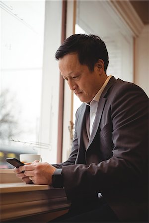 simsearch:6109-07600968,k - Businessman using mobile phone while sitting by window in coffee shop Stock Photo - Premium Royalty-Free, Code: 6109-08945410