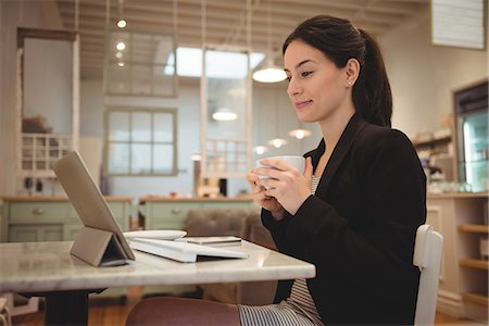 simsearch:693-07456264,k - Businesswoman having coffee while looking at digital tablet in cafe Stock Photo - Premium Royalty-Free, Code: 6109-08945412