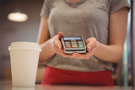 simsearch:6126-09104476,k - Midsection of female barista holding credit card reader in coffee shop Stock Photo - Premium Royalty-Free, Code: 6109-08945427