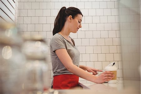 simsearch:614-08946547,k - Side view of female barista holding coffee cup while using tablet PC in coffee shop Foto de stock - Sin royalties Premium, Código: 6109-08945424