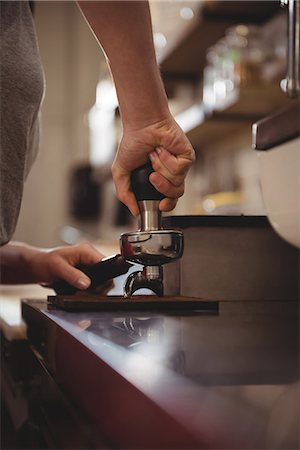 simsearch:6109-08945337,k - Cropped image of female barista tamping coffee in cafe Fotografie stock - Premium Royalty-Free, Codice: 6109-08945428